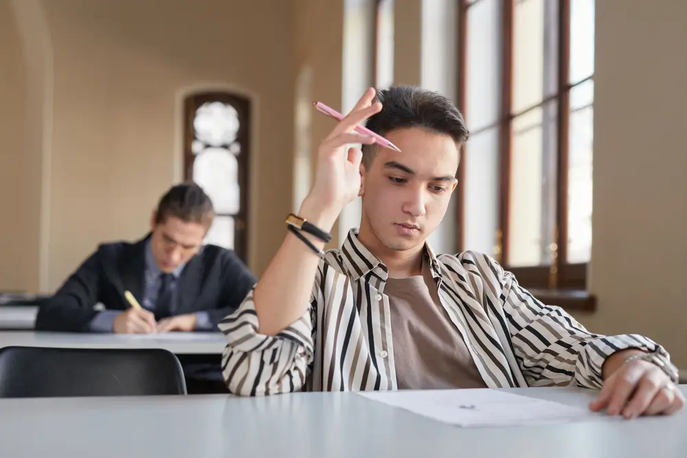 Candidati concentrati durante lo svolgimento della prova scritta di un concorso pubblico in aula.