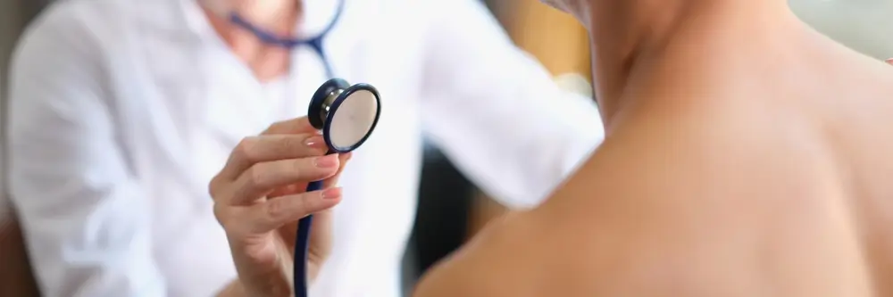 Medico sportivo esegue un controllo cardiaco con lo stetoscopio durante una visita per l'idoneità agonistica.