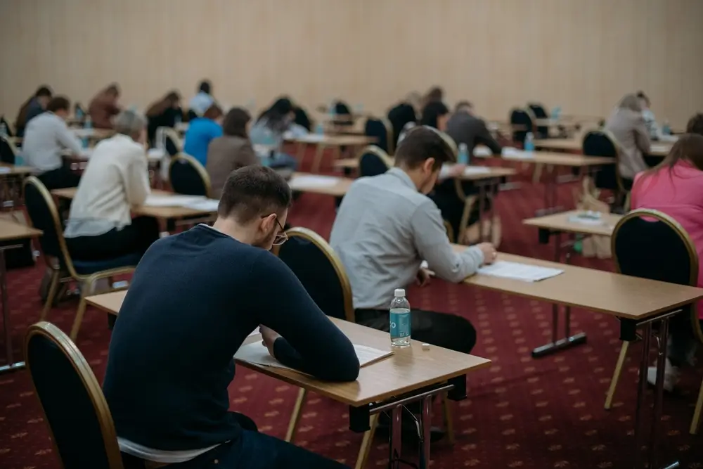 Candidati seduti ai banchi durante lo svolgimento della prova scritta in un'aula dell'accademia di polizia.