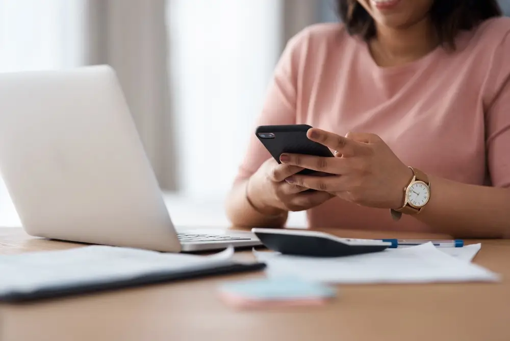 Persona che utilizza uno smartphone e un laptop per inviare la domanda di concorso online.