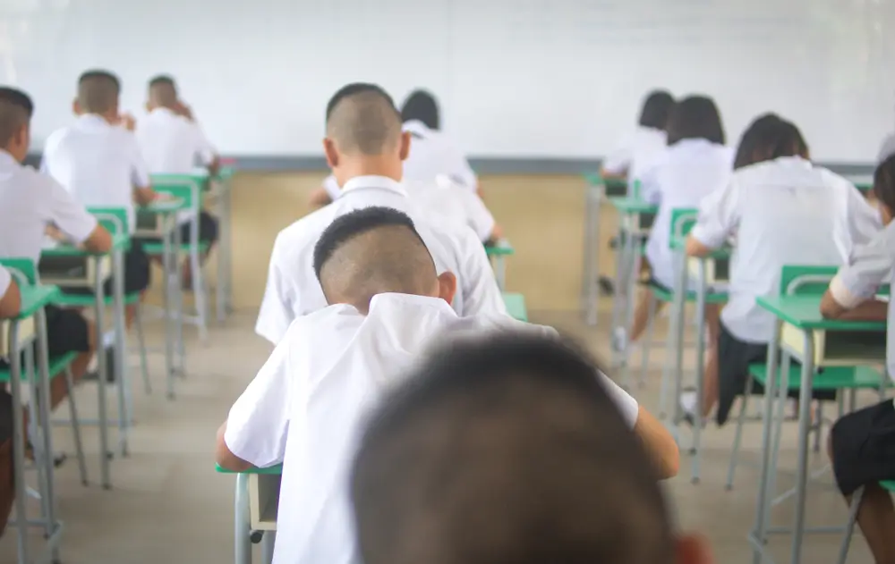 Candidati concentrati sui banchi di un'aula durante lo svolgimento della prova scritta di un concorso pubblico.