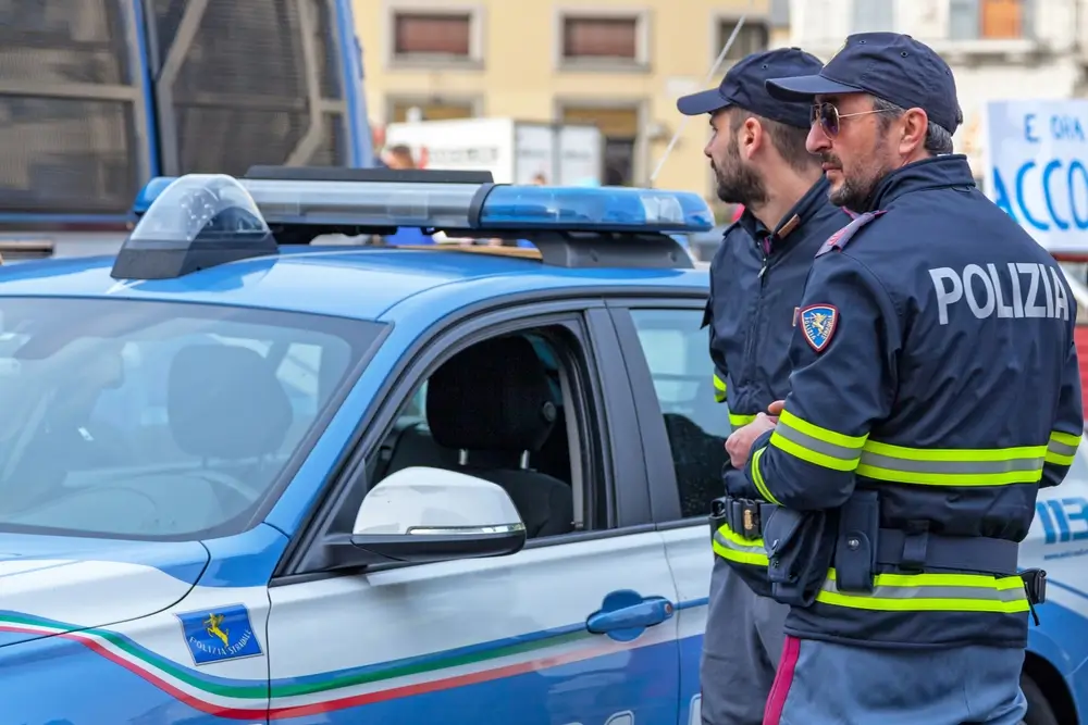 Due poliziotti della Polizia di Stato in servizio di controllo del territorio in città accanto a una volante.