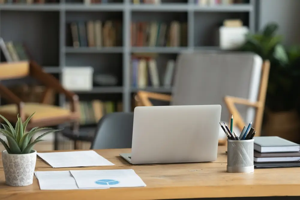 Laptop e documenti su una scrivania in legno, postazione ideale per lo studio del diritto in un ambiente professionale.