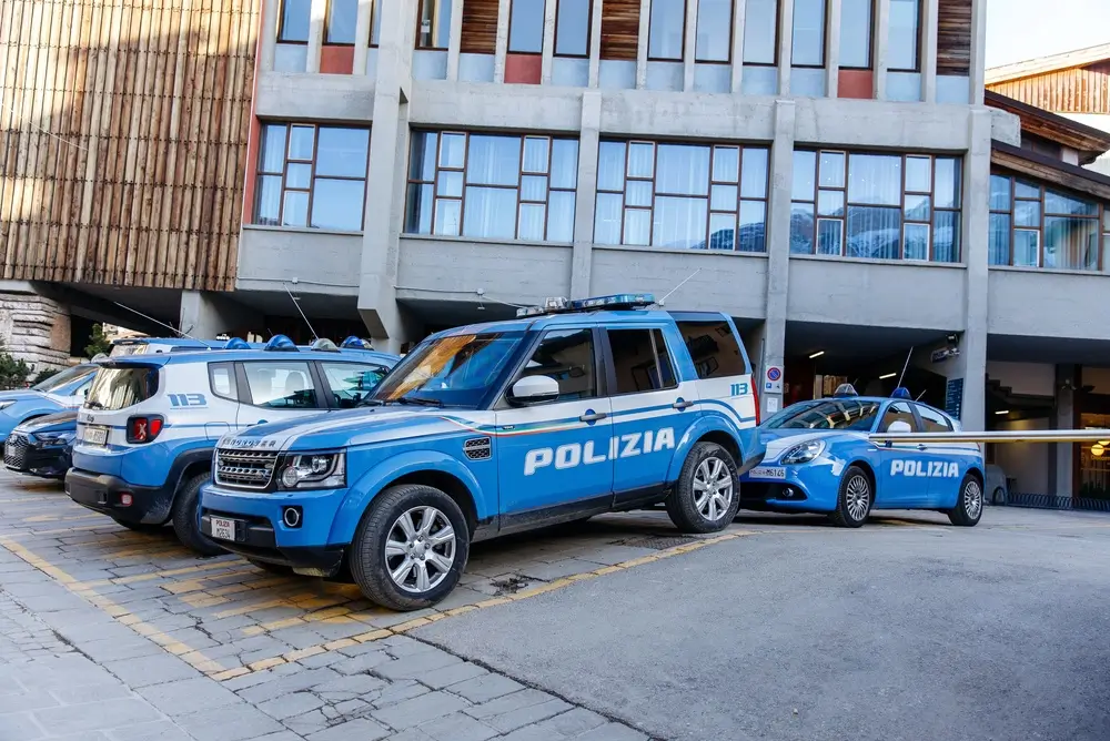 Auto di pattuglia e SUV della Polizia di Stato parcheggiati davanti all'ingresso di un commissariato.