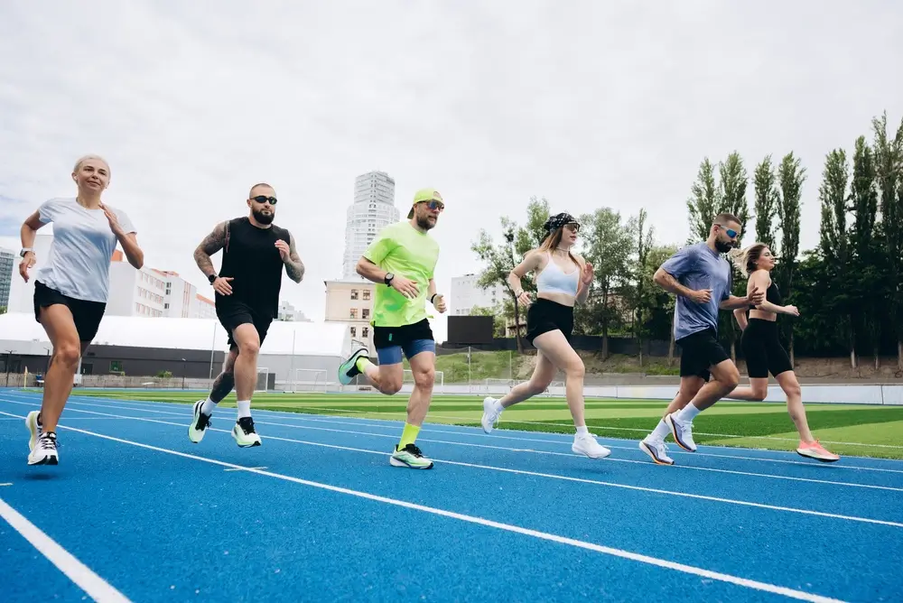 Candidati impegnati nella corsa su una pista di atletica durante la prova fisica per un concorso in polizia.